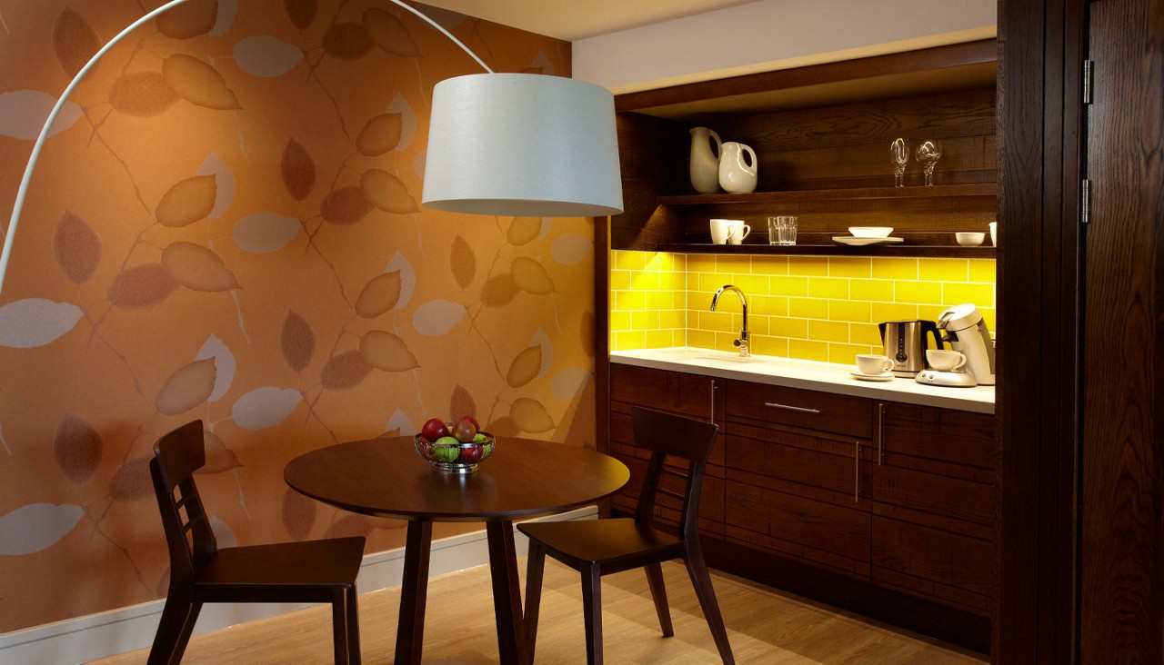 Table and chairs beside a beverage station..