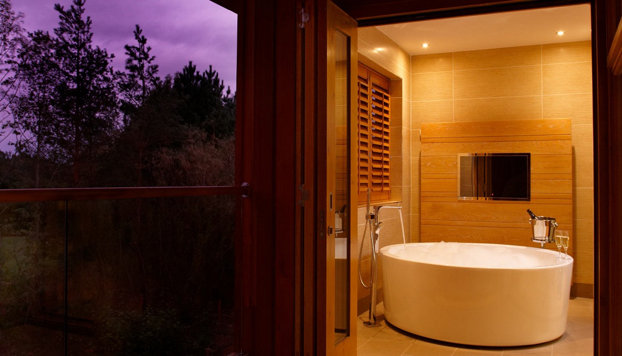 Large bubble bath adjoining a balcony with views out to the forest.