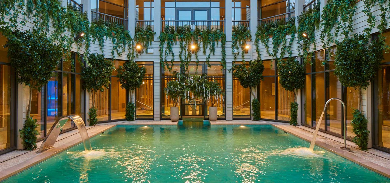 Outdoor pool surrounded by hanging plants.