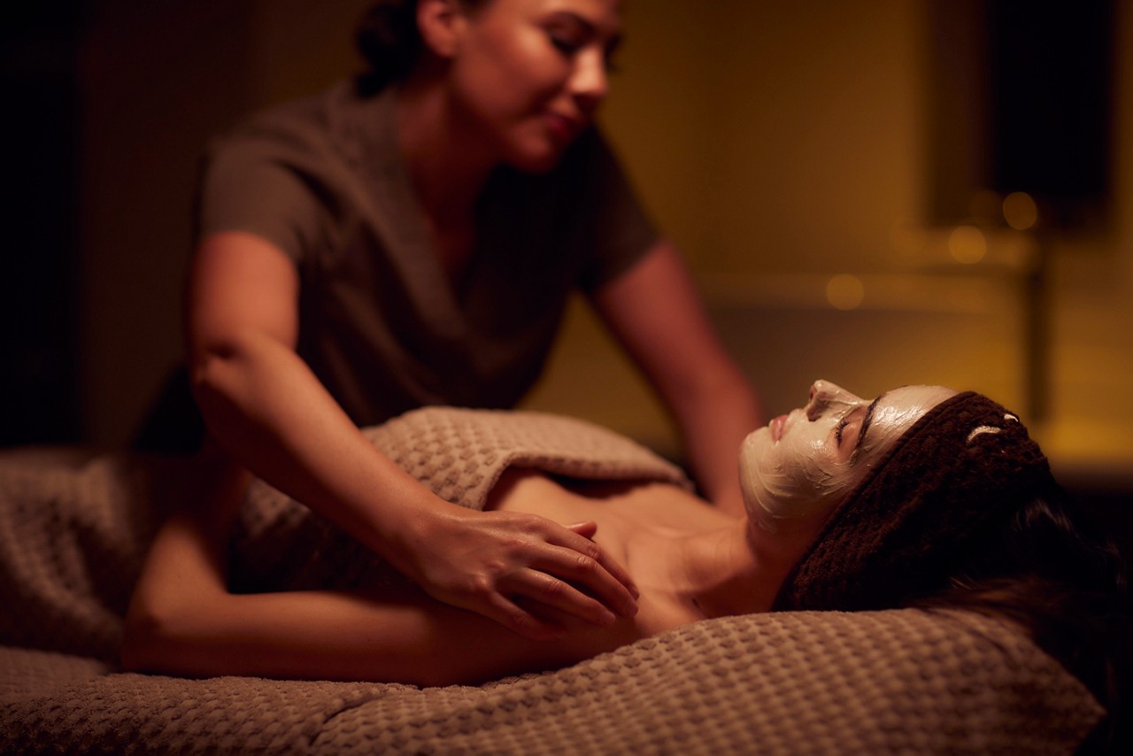 Spa therapist giving a woman a face mask treatment.