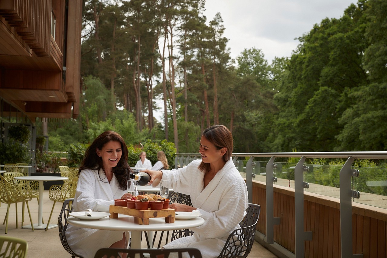 Two ladies sharing a Vitalé Platter on a balcony surrounded by the forest.