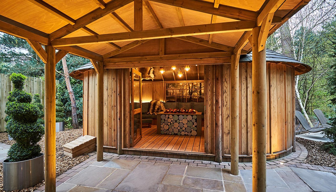 Scandinavian Snug with a central glowing fire nestled in the surrounding forest garden.