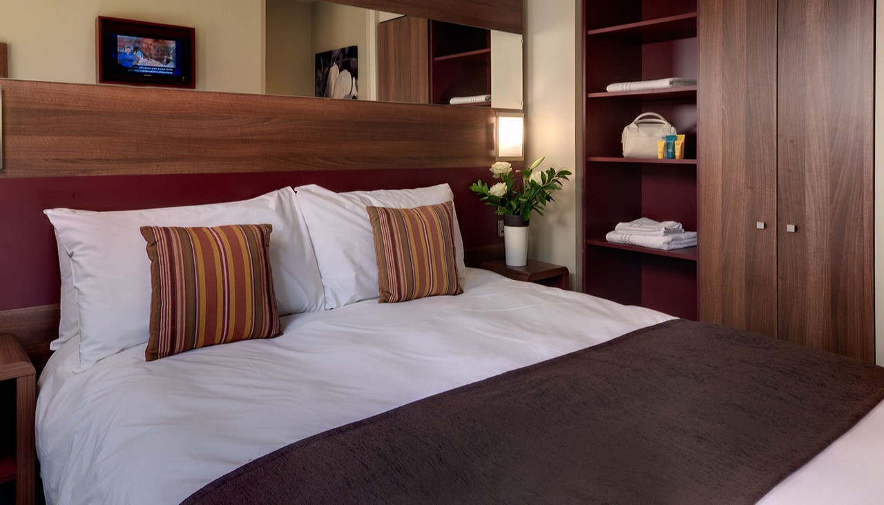 Double bed in a room with fresh flowers and built in storage. 