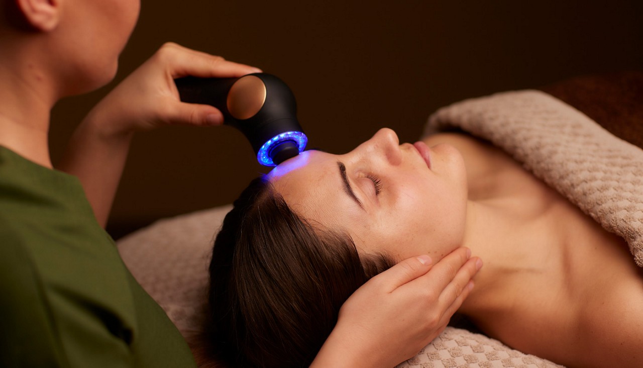 Woman having a facial with a microcurrent handheld device.