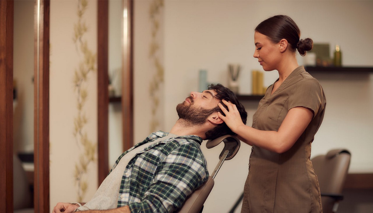Man laid back having his head massaged.