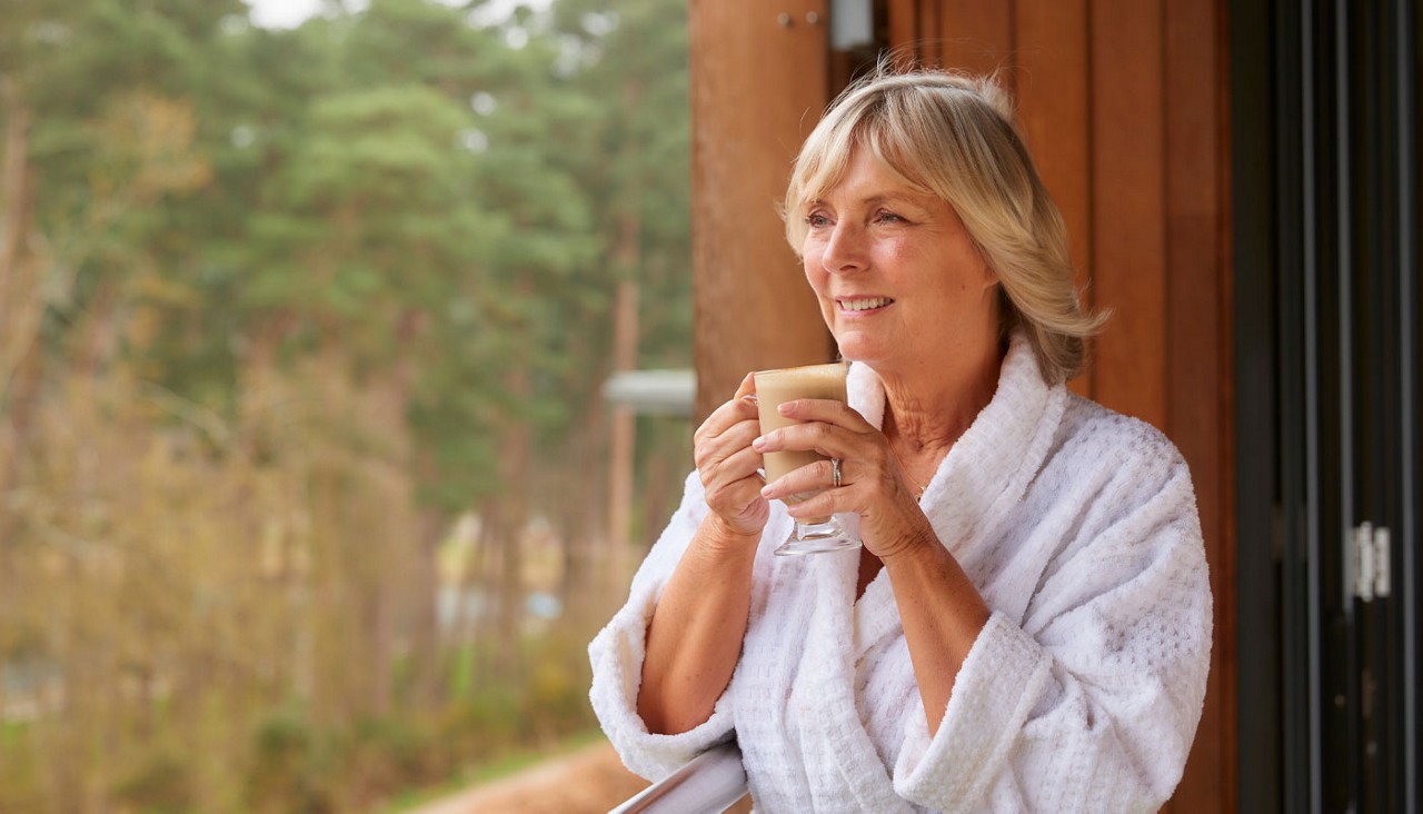 Woman drinking a coffee whilst looking out to the forest