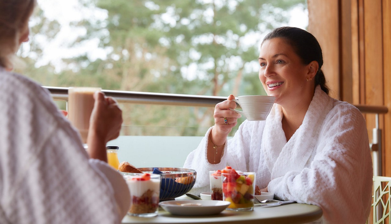 Two women sitting on a Spa Suite balcony enjoying breakfast together