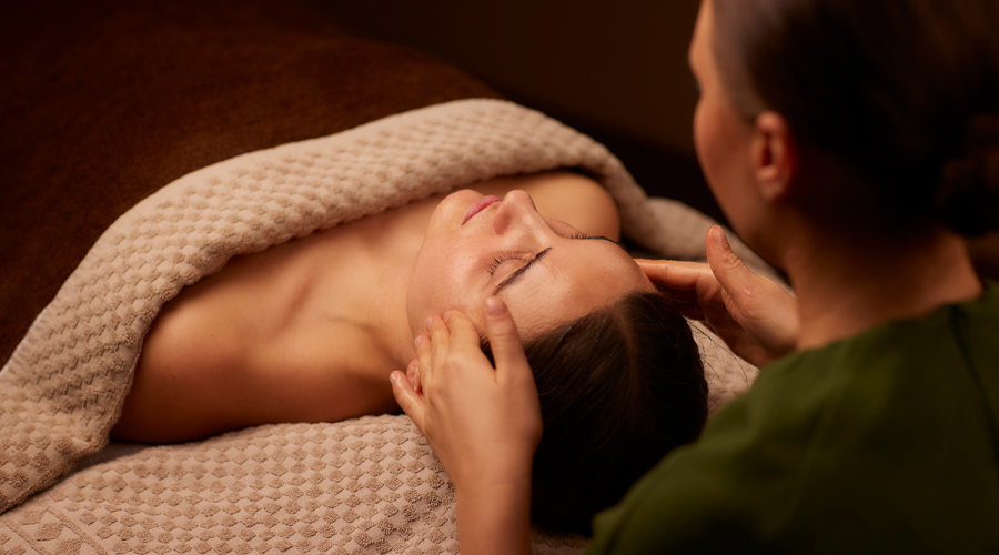 Spa therapist giving a women a relaxing face and body treatment.