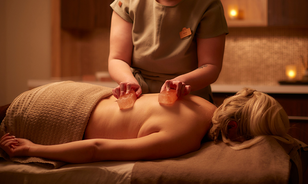 Woman having salt blocks placed on her back.