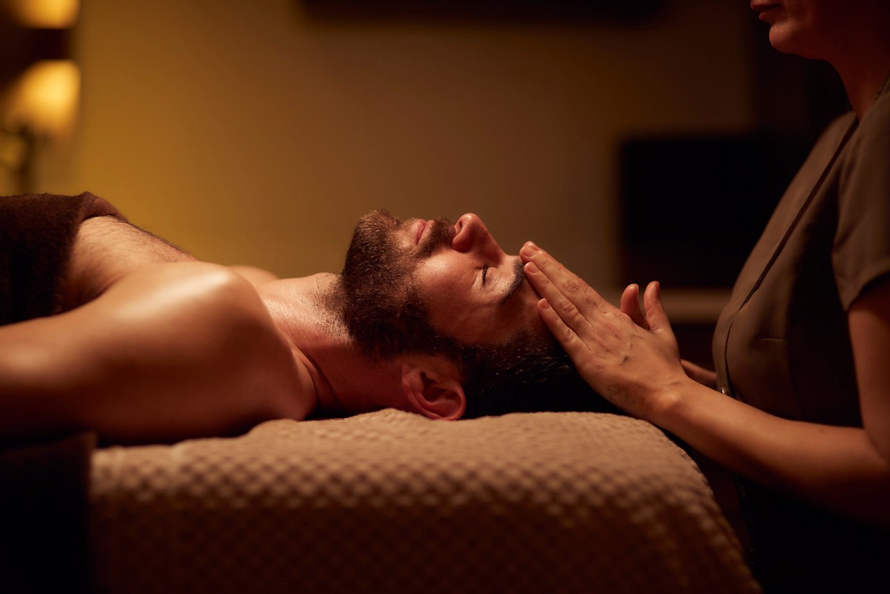 Spa therapist giving a man a relaxing massage treatment whilst lying on a spa bed