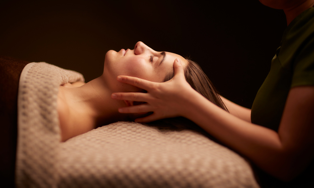 Spa therapist giving a woman a relaxing face and body treatment.