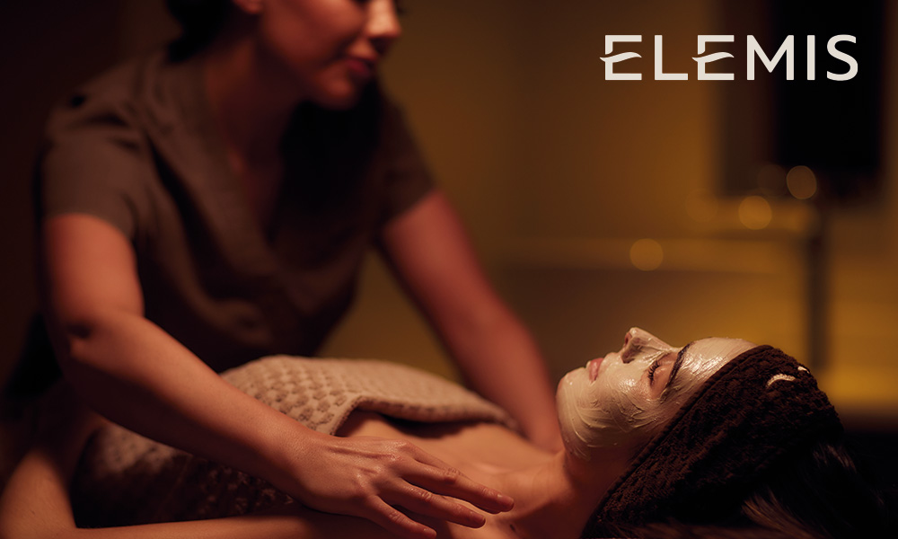A massage therapist massaging shoulders of a lady with a face mask on
