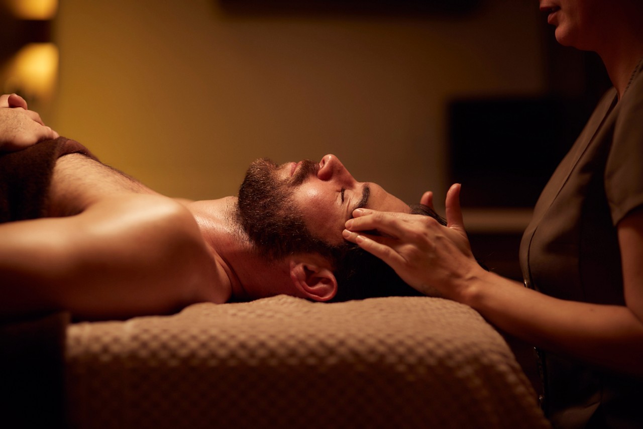 Spa therapist giving a man a relaxing facial treatment.