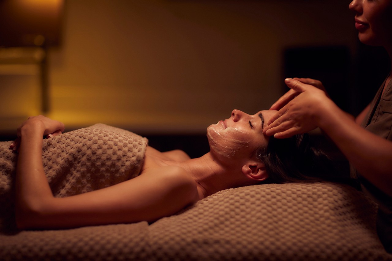 Spa therapist giving a woman a facial treatment.