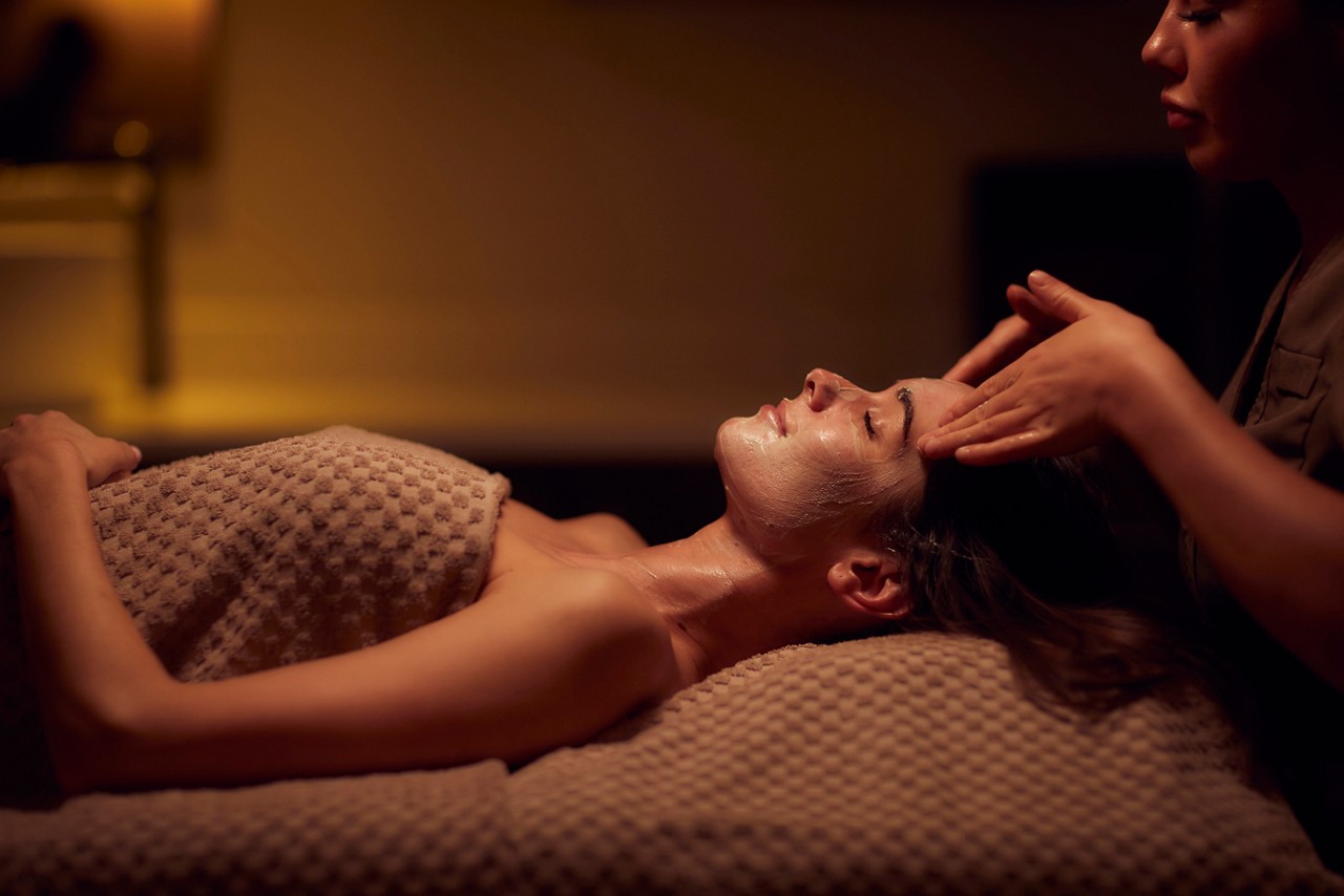 Spa therapist giving a woman a facial treatment.