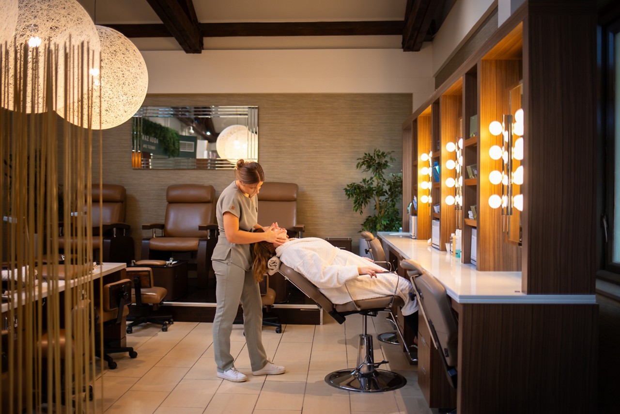 A therapist giving a facial treatment to a pregnant client reclining in a spa chair