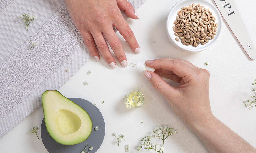 hand with painted finger nails and cuticle oil being applied