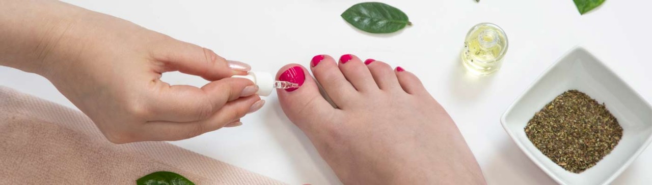 foot with painted toe nails with cuticle oil being applied