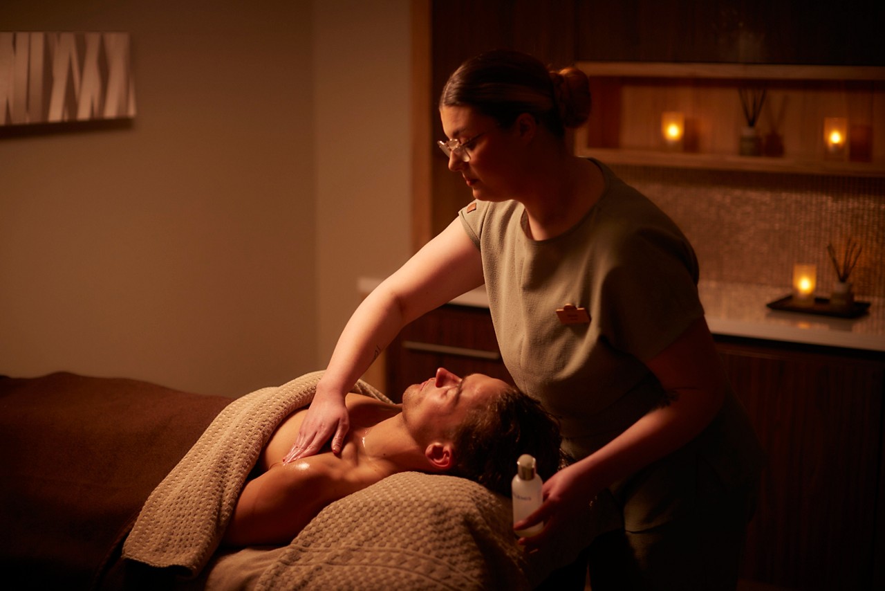 Spa therapist giving a person a body massage treatment.