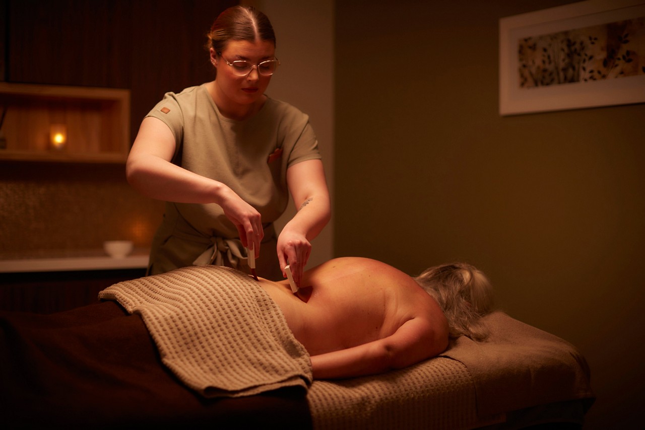 A massage therapist performing a comfort zone tranquility pro sleep wellbeing massage on a client lying on a treatment table