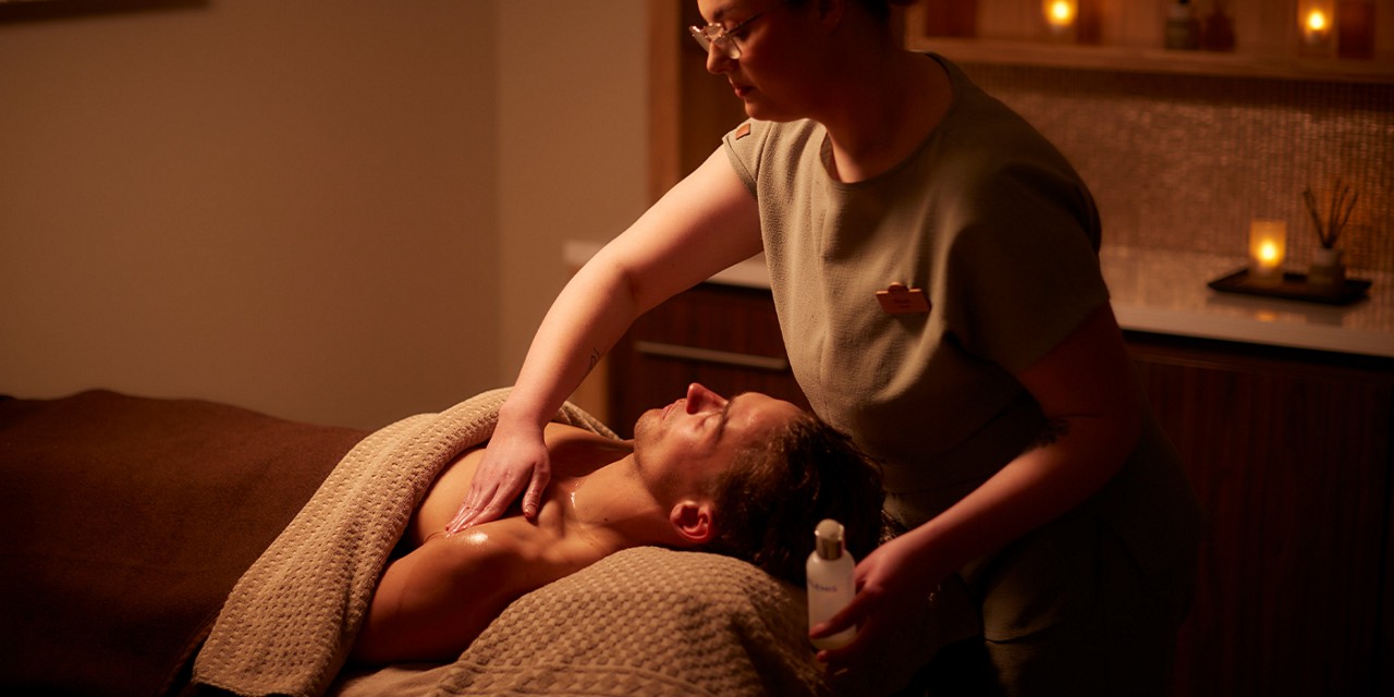 Woman applying products to a person laid in a treatment room.