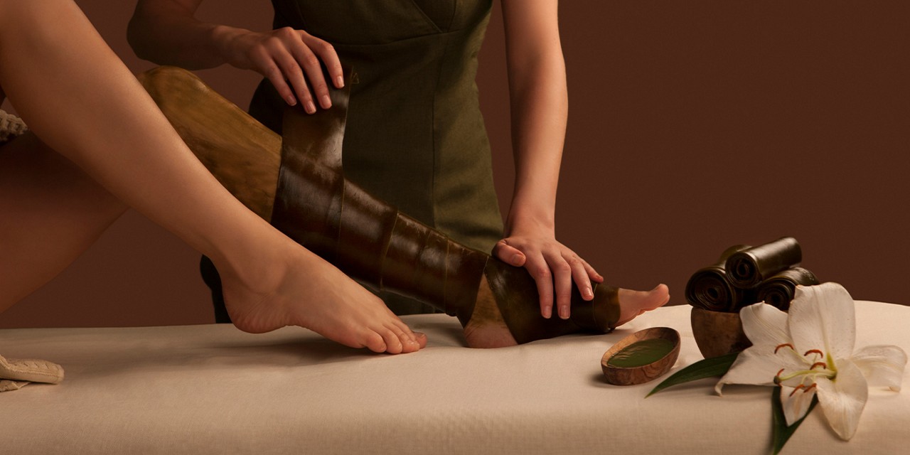 Someone having their leg wrapped in seaweed.